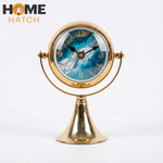 Luxury golden metal table clock with ocean-themed dial on white background