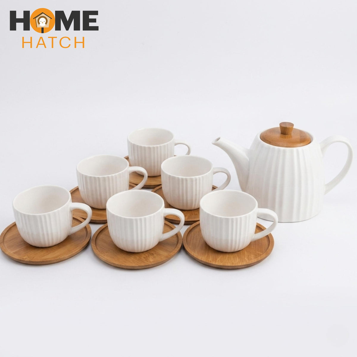 Set of white ceramic cups and a teapot with wooden accents on a light gray background