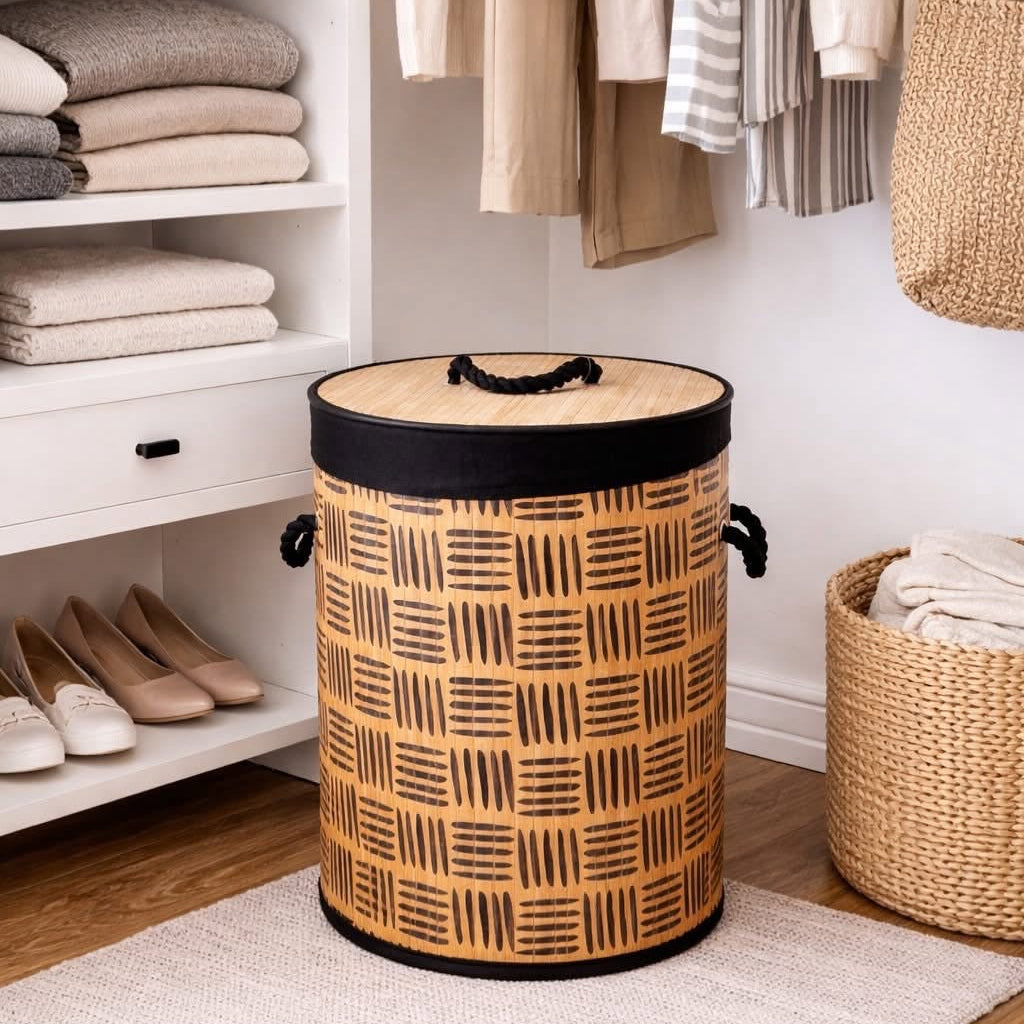 A cylindrical woven storage basket with a black and tan basketweave pattern, black trim, and side handles, placed on a rug in a styled closet or storage area.